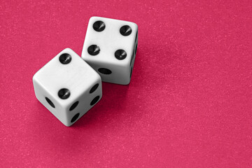 Pair of white dice with black dots on a bright red textured background. Representing luck, chance, gaming, probability and decision-making in gambling and board game concepts.