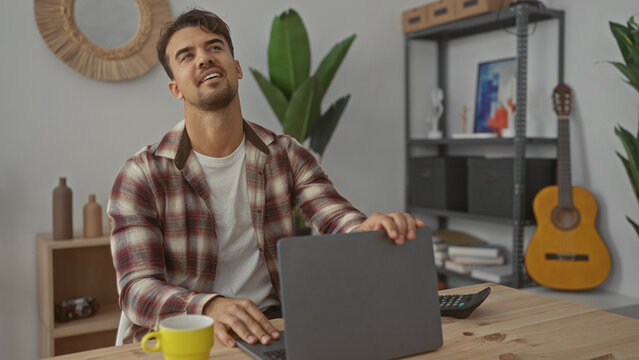 Young man working in a cozy office surrounded by plants and a guitar, exuding a focused and relaxed atmosphere.