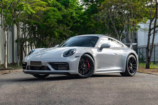 White Porsche 911 Carrera GTS front view three quarters, Sports car parked on tree-lined road