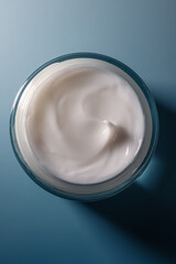 Skincare cream smoothing texture in glass jar on blue background for beauty and cosmetic concepts