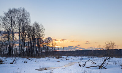 Snowy landscape with a river and trees in the background