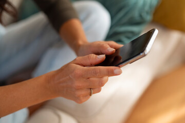 Obraz premium A close-up of a woman’s hands holding and using a smartphone while sitting at home. 