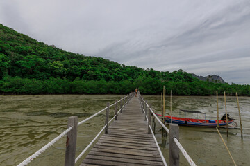 Wooden bridge spans a body of water, with a boat docked on the other side
