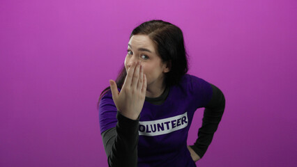 Woman making a gesture of calling with her hand wearing a volunteer shirt against a vibrant pink background.
