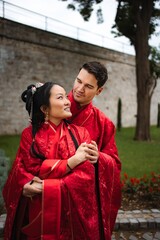 Obraz premium Interracial wedding couple embracing wearing traditional Chinese attire