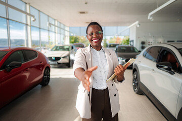 Fototapeta premium Car saleswoman offering handshake in modern dealership showroom