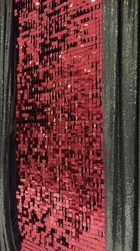 Vibrant red square sequins shimmering beside dark green sequin drapes. Subtle breeze adds motion and sparkle. Perfect for festive, glamorous, or holiday-themed backgrounds and overlays.