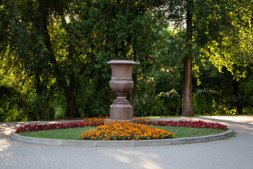 A large decorative stone garden vase placed in the center of a landscaped park in Chisinau, Moldova.