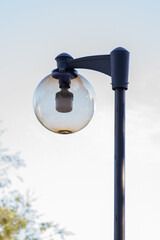 A round street lamp captured against a clear sky. The minimalistic composition emphasizes clean lines, soft daylight, and urban design elements