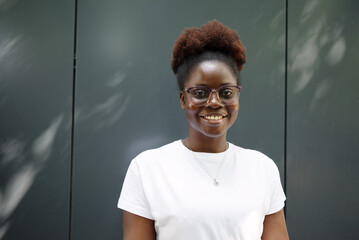 Confident young woman standing outdoors, smiling at the camera in an urban setting.