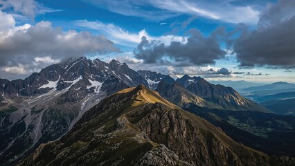 Fototapeta premium Mountain landscape with rugged peaks, clouds, and blue sky, showcasing natural beauty and geological features.
