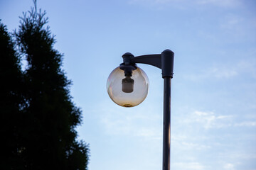 A round street lamp captured against a clear sky. The minimalistic composition emphasizes clean lines, soft daylight, and urban design elements