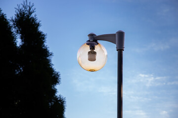 A round street lamp captured against a clear sky. The minimalistic composition emphasizes clean lines, soft daylight, and urban design elements