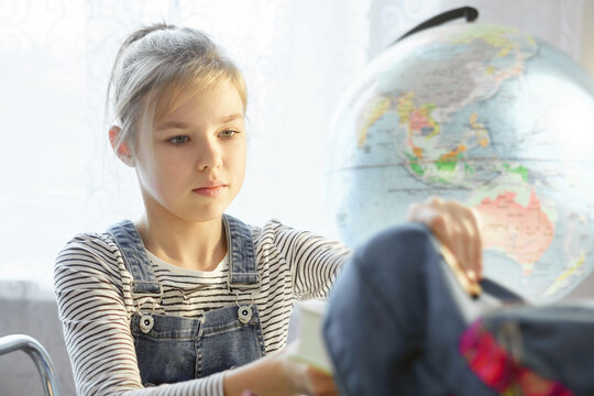 School girl packing books in backpack at the table for school after finishing homework, back to school concept