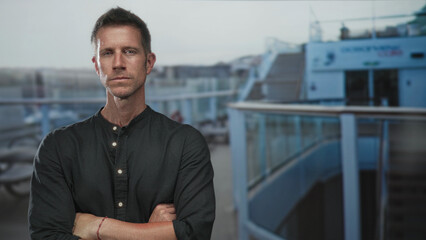 Fototapeta premium Man with arms crossed on cruise deck near glass railing, stern expression and folded forearms visible; quiet determination.