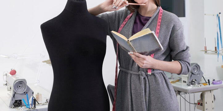 Cropped view of seamstress measuring black dummy in workshop, tailor studio work