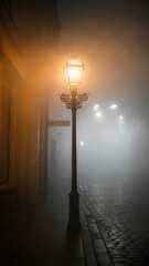 Street lamp glowing in the fog on a cobblestone street in a city at night