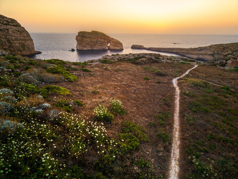 Scenic sunset view over the cliffs of Gozo, Malta with a coastal path and rock formations