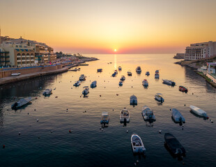 Beautiful sunset over calm waters in Paceville, Malta with boats at rest