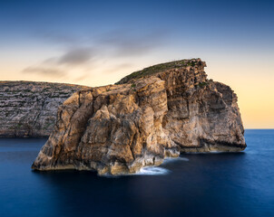Breathtaking sunset view of Gozo's Fungus Rock surrounded by calm waters