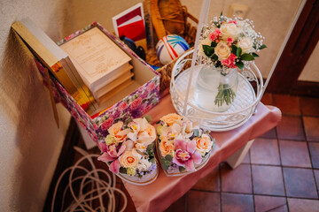 Floral arrangements in decorative containers, a bouquet in a glass vase, and a box of stationery create a charming display on a table with warm lighting and inviting ambiance