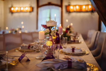 Elegant dining table set for a festive celebration, adorned with candles, floral arrangements, and decorative tableware, creating a warm and inviting atmosphere for guests