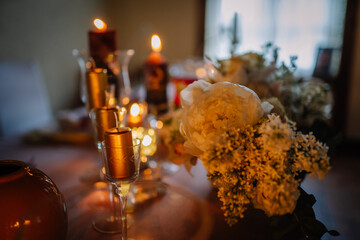 Elegant floral arrangement featuring peonies and candles on a beautifully set table, creating a warm and inviting atmosphere for a special occasion or celebration