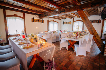Elegant dining room set for a festive celebration, featuring beautifully arranged tables with floral centerpieces, candles, and soft lighting creating a warm atmosphere