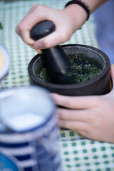 Frische Kräuter werden im Mörser von Hand zerkleinert für die Küche