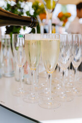 Sparkling wine poured into champagne flutes at an outdoor event, bubbles rising