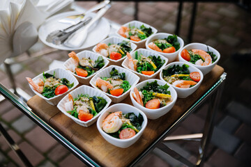 Mini shrimp seaweed salads in white bowls on a catering tray at an outdoor event