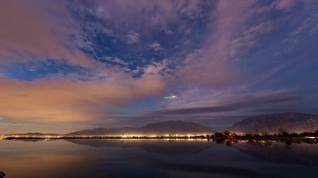 Timelapse from Utah Lake State Park at night over the city as planes fly through the sky.