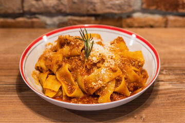 Delicious plate of pappardelle Bolognese topped with rich meat sauce and garnished with rosemary and grated Parmesan cheese