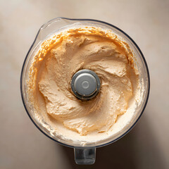 Top-view shot of a blender filled with creamy whipped cottage cheese and peanut butter mousse, showing smooth texture with a hint of the silver blade on a clean countertop under bright lighting.