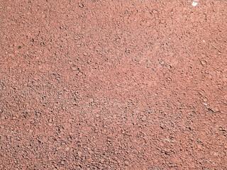 Fondo de textura granular y porosa de color rojo terracota, ideal para pistas de deporte