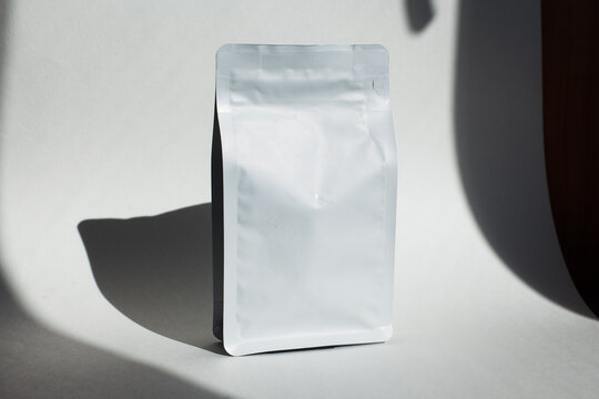 Blank craft plastic pouch, white pack on studio background with shadow, mylar bag isolated for coffee or food, cosmetic products, snack, candy. Different sizes, mock up.