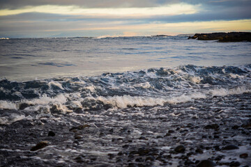 Waves on a rocky beach under cloudy sky