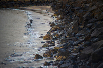 Rocky shoreline with gentle waves and wet sand