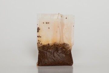 Close-up of a wet tea bag with tea leaves on a white