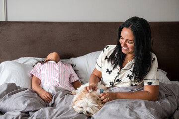 A woman and a child are laying on a bed with a dog