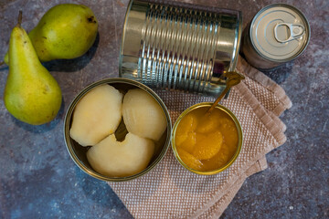 Canned pears and mandarin segments contrasted with two fresh pears, arranged on a rustic background. 