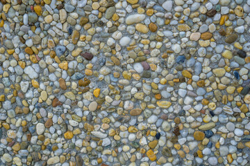 multicolored exposed aggregate texture closeup showing small round river stones embedded in grey cement concept of construction material, landscaping, exterior design