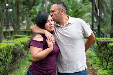Fototapeta premium a tender kiss on the head as a couple is photographed in a park