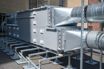 A ventilation unit rests on steel supports on the building's roof.