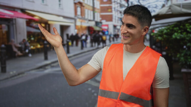 Man holds up three fingers hand gesture wearing orange safety vest on a busy city street market with visible forearm and hand; friendly.