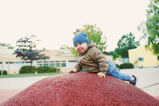 Young child explores a colorful playground hill on a sunny day with joyful determination in an outdoor setting