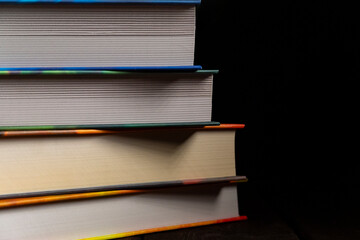 Stack of colorful hardcover books on black background
