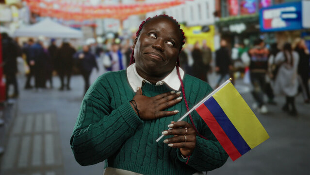 Woman holding colombian flag on vibrant city street, expressing joy and pride, with diverse crowd in background, representing multicultural celebration outdoor.