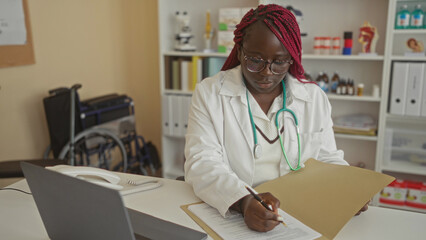 African american woman doctor writing notes in a hospital office, surrounded by medical equipment...