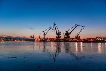 Obraz premium Industrial harbor cranes reflecting in evening water.